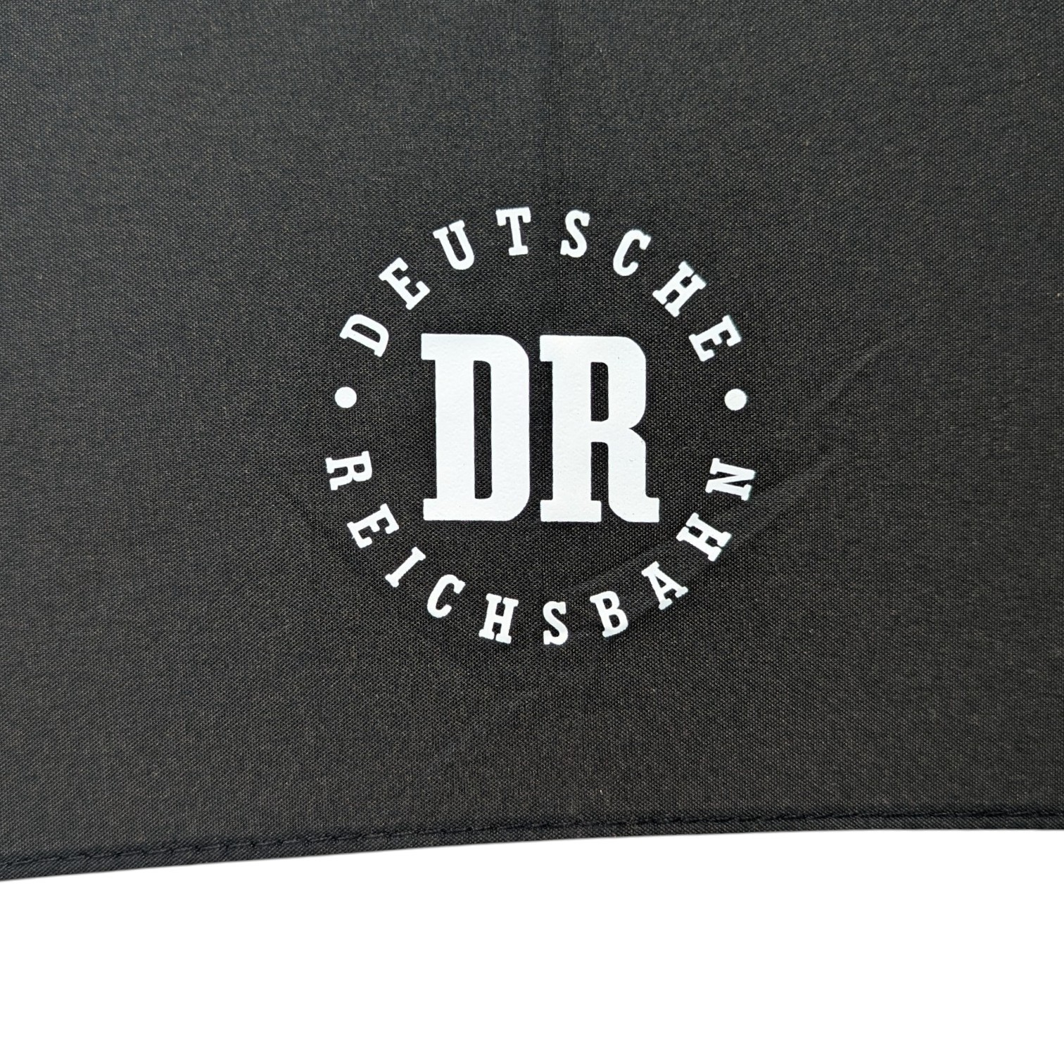 Weißes DR-Logo der Deutschen Reichsbahn auf schwarzem Stockschirm, Detailansicht